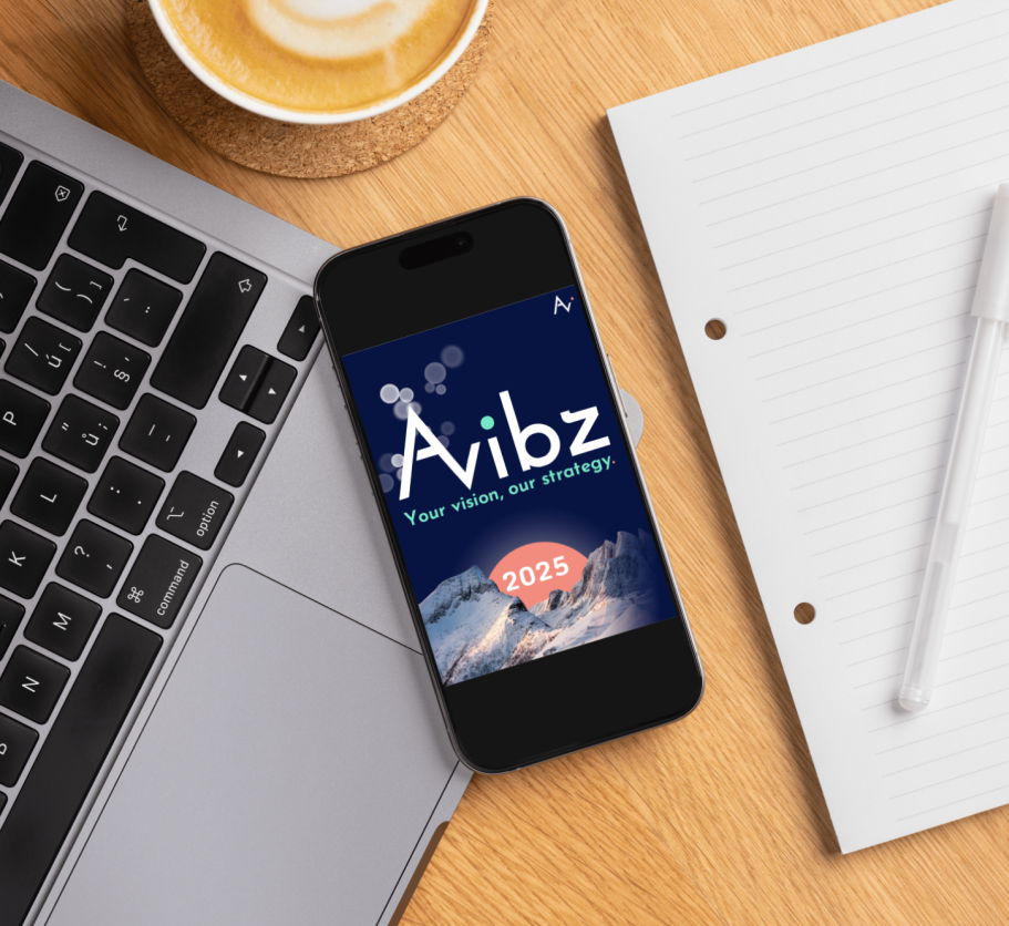 Découvrez notre nouvelle brochure! Téléphone portable affichant l'application Avibz sur un bureau avec un ordinateur et un café.